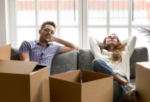 Happy Paar auf Sofa mit leeren Umzugskartons